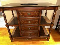 Front view of black bathroom vanity showing wood base with three drawers and two open shelves