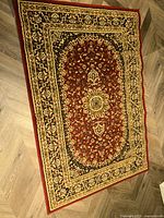 Full view of the rectangular area rug showing the central floral medallion pattern and border design on a wood floor.
