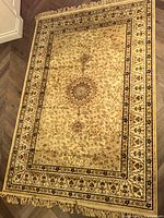 Top-down view of the full cream ornate area carpet showing central medallion and floral patterns.