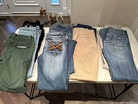 Ten pairs of ladies size 3 pants including jeans and casual styles, laid out on a table to show variety and condition.