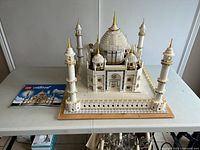 Front-left angle of assembled Taj Mahal model on base with instruction manual visible