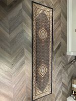 Top-down photo of the full navy and cream carpet runner showing detailed pattern and edges on a herringbone floor.