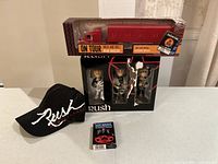 Photo showing the full lot including Rush bobbleheads set, black hat, playing cards, and tour tractor trailer