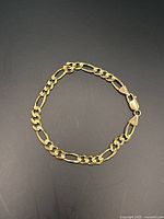 Bracelet laid flat on dark background showing overall chain style and shape