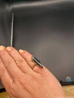 Ring worn on finger showing the marquise-shaped hematite stone and gold band