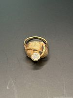 Top view of ring showing knot design and central stone on black surface