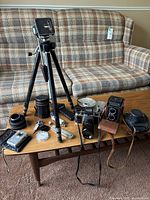 Overview of entire lot including tripod, cameras and accessories on table