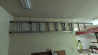 Full view of the aluminum extension ladder mounted horizontally on a wall, showing entire length and structure.