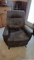 Front view of brown micro suede power lift chair with remote on seat.