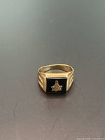 Front view of Masonic signet ring with black onyx and gold square and compass emblem