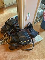 Photo showing several black ladies purses piled on box next to mirror, mostly crossbody style with some textured finishes