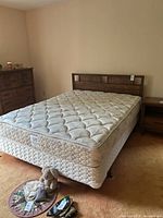 Overall view of queen bed with mattress on wooden headboard and metal frame