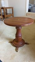 Full view of round wooden table showing top and pedestal base with claw feet
