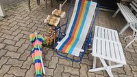 Photo showing the beach chair with multicolor striped fabric, beach umbrella, wooden croquet set and white resin tables under a covered patio.