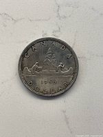 Obverse side of the 1966 Canadian silver dollar coin showing the canoe and voyageurs design with year and CANADA DOLLAR inscriptions.