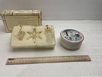 Three Avon glass ornaments (angel, star, snowflake) in foam inside original box, with Villeroy and Boch Christmas-themed round trinket box next to it and ruler for scale.