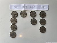 Photo of 10 Buffalo Nickels grouped by year: 1920 (4 coins), 1924 (1 coin), 1925 (2 coins), 1926 (3 coins). Coins show heavy wear and tarnish.