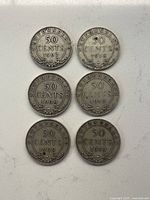 Front view of six Newfoundland 50 cent coins dated 1907, 1918 (two coins), 1908, 1909, and 1919 arranged in pairs on a white surface.