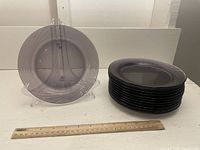 Stack of 12 amethyst Pyrex glass plates with a ruler for scale, showing the thickness and size of the plates.