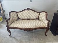 Full front view of the vintage carved wood settee sofa showing carved wood frame and floral upholstery