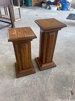 Pair of solid oak plant stands/end tables, one 22 inches tall, one 24.5 inches tall, shown standing side by side.
