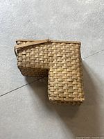 Wicker stair basket showing side profile with handle and natural woven wicker material