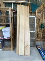 Three long pine boards standing upright against a wall with visible wood grain and knots.