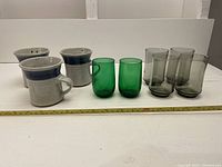 Photo showing all 10 items: 3 pottery mugs in beige and blue, 3 green juice glasses, and 4 tawny MCM juice glasses.