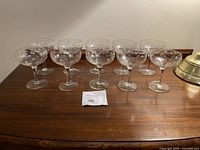 Full set of 10 crystal stemware glasses arranged in two rows on a wooden surface.