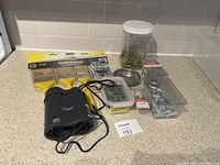 Top view of all items including Airman electric pump, three yellow paint brushes, jar of green screws, plastic trays with assorted screws, metal dish, and small container.