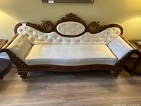 Full view of antique sofa settee with cream upholstery and carved wooden frame.