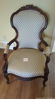 Front view of Victorian chair showing detailed upholstery and carved wooden frame