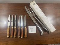 Six Birks knives with antler handles and two hollow carving tools next to original box on wooden surface