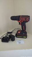 Black & Decker cordless drill with battery and charger on shelf