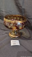 Photo showing front and side view of the Bohemian crystal pedestal bowl with detailed strawberry vine etching and gold bands on a dark background.