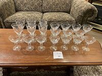 Full set of 20 crystal stemware glasses on a wooden table, showcasing the different heights arranged in rows.