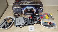 Full view of assembled LEGO DeLorean time machine with pieces and box in background