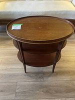 Front view of the wooden MCM oval end table showing top surface and lower shelves.
