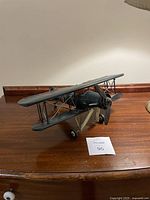 Side angle view of the blue-gray metal biplane with detailed wing struts and double wings showing propeller and landing gear.