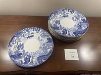 Eight plates arranged on wood table with lot tag visible