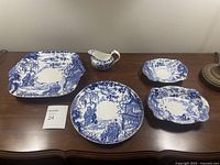Full set of six blue and white Royal Crown Derby serving dishes displayed on wooden table.