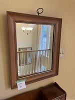 Full view of the rectangular wall mirror mounted on wall showing the entire mirror and frame with reflection of surrounding room.