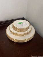 Stacked set of Wedgwood plates in three different sizes showing the gold rims and white base.