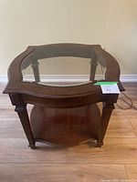 Top view of wood and glass end table showing decorative curved glass insert and dark wood frame.