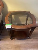 View of wood and glass end table from an angle showing side and top edges, with the glass inset and wooden frame with wavy edges.