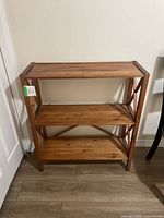 Full view of wooden shelving unit with three shelves and visible wear