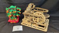 Wooden marble track puzzle with gears alongside Lego Money Tree set on black background