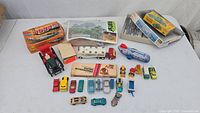 Overview of the lot featuring multiple vintage diecast toy vehicles, boxes, and models including an RV trailer and a red tractor model.