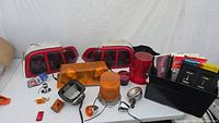View of all items on table including taillights, light bar, warning lights, and black bin with manuals and small parts.