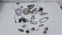 Various 1950s Chevrolet car parts including mirrors, light fixtures, trim pieces all arranged on a table